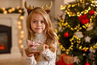 Little girl with Christmas gift at home