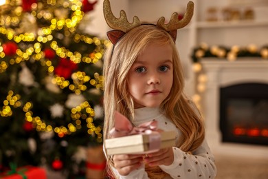 Photo of Little girl with Christmas gift at home