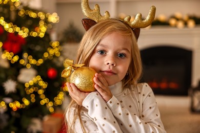 Photo of Little girl with Christmas ornament at home