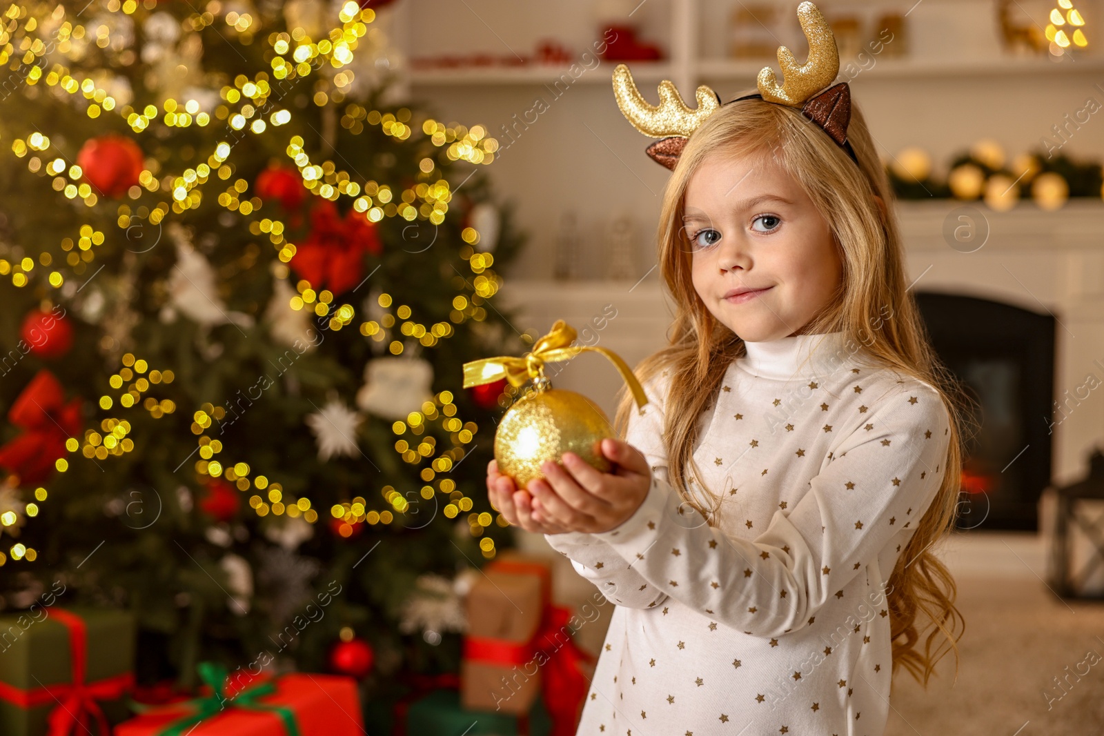 Photo of Little girl with Christmas ornament at home, space for text