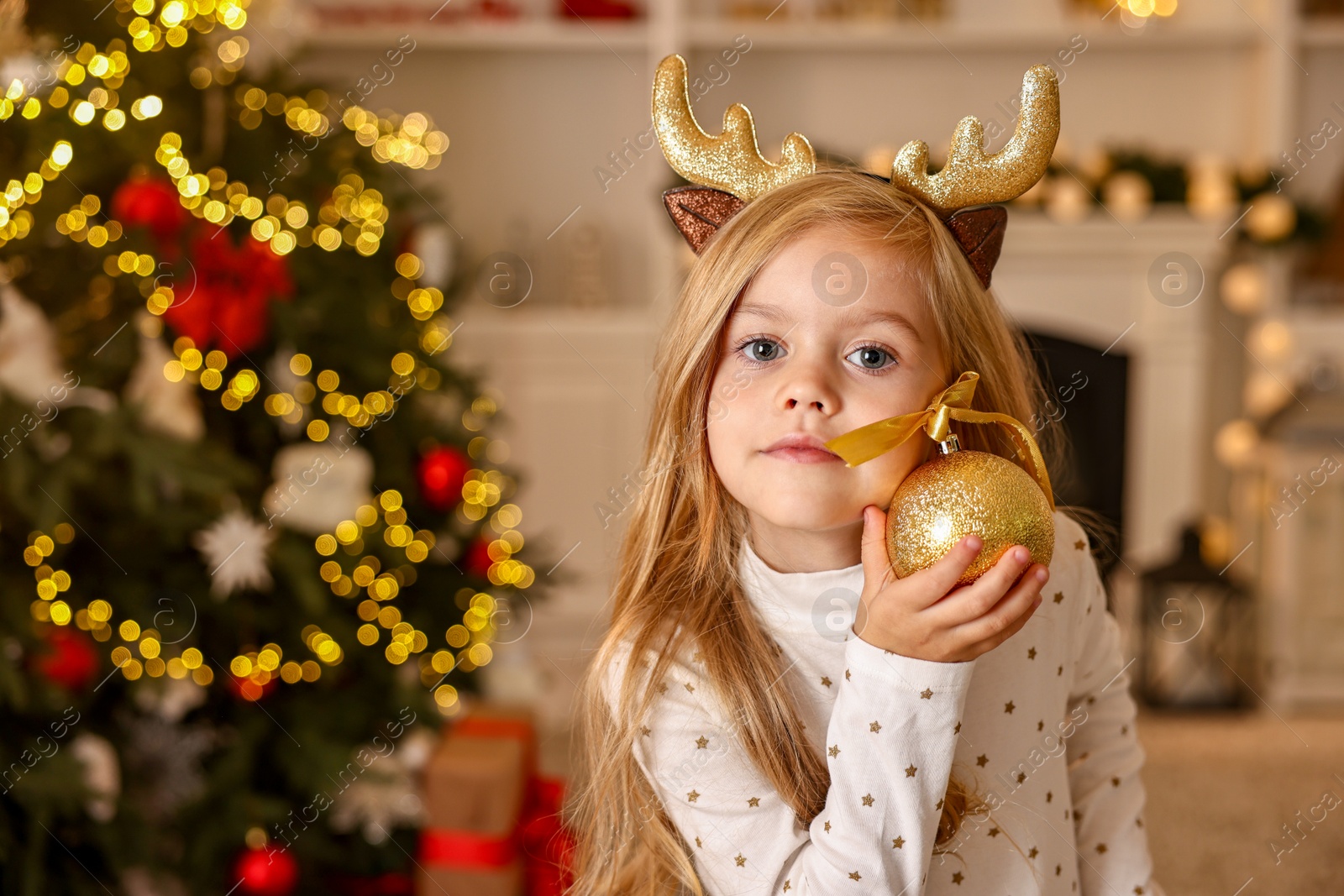 Photo of Little girl with Christmas ornament at home, space for text