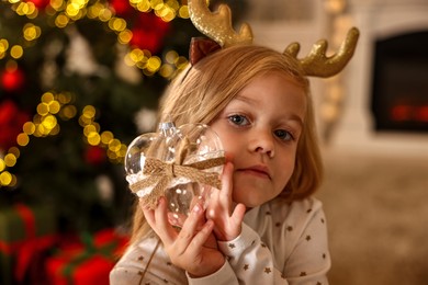 Photo of Little girl with Christmas ornament at home