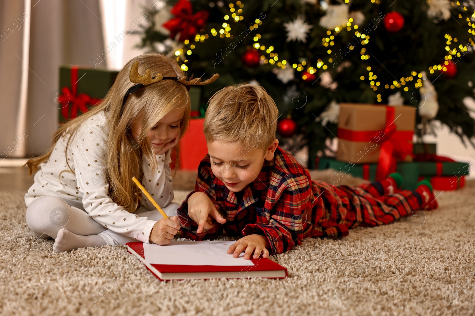 Photo of Little kids writing letter to Santa Claus on floor at home. Christmas celebration