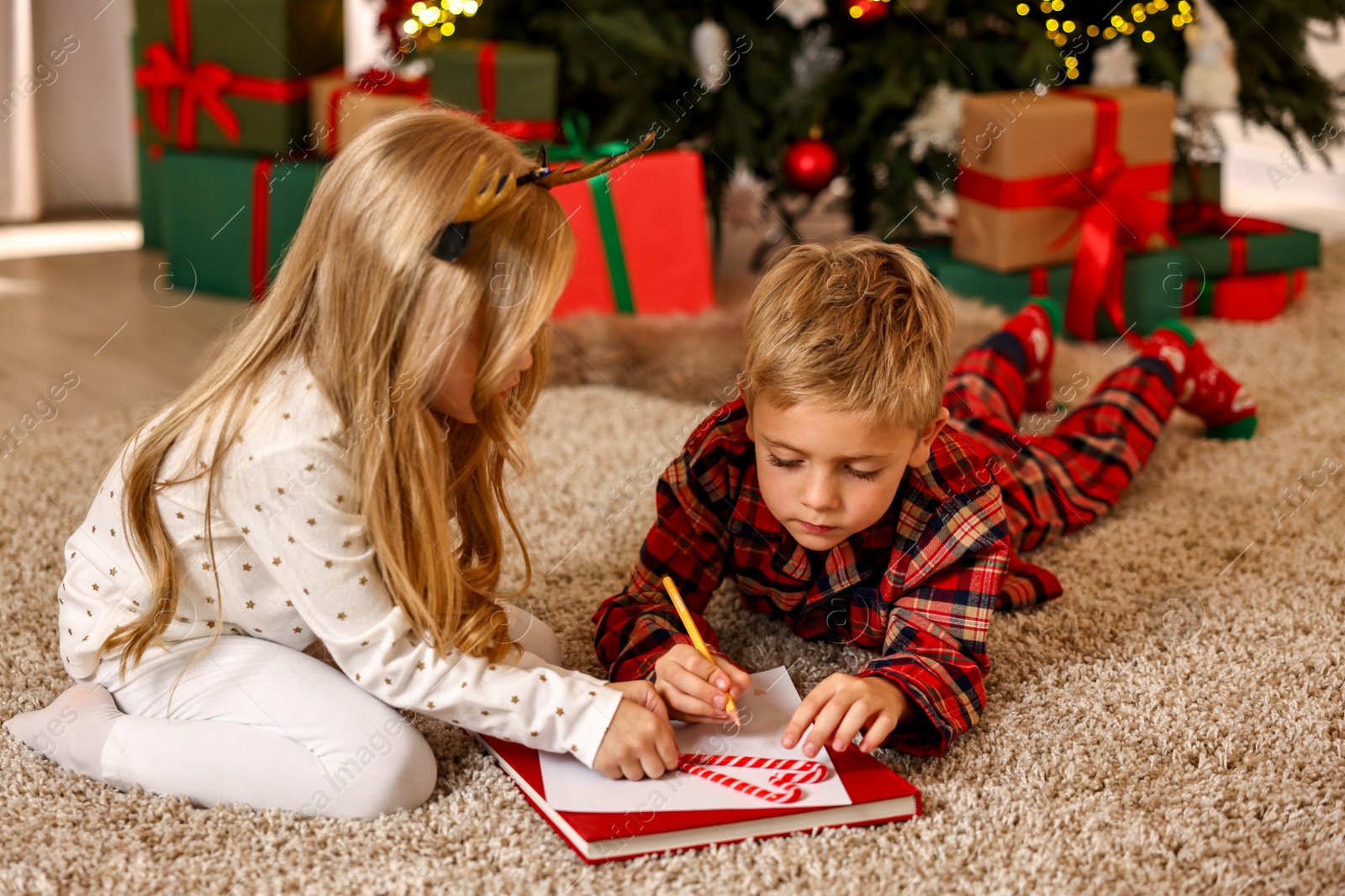 Photo of Little kids writing letter to Santa Claus on floor at home. Christmas celebration