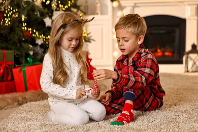 Little kids with candy canes on floor at home. Christmas celebration