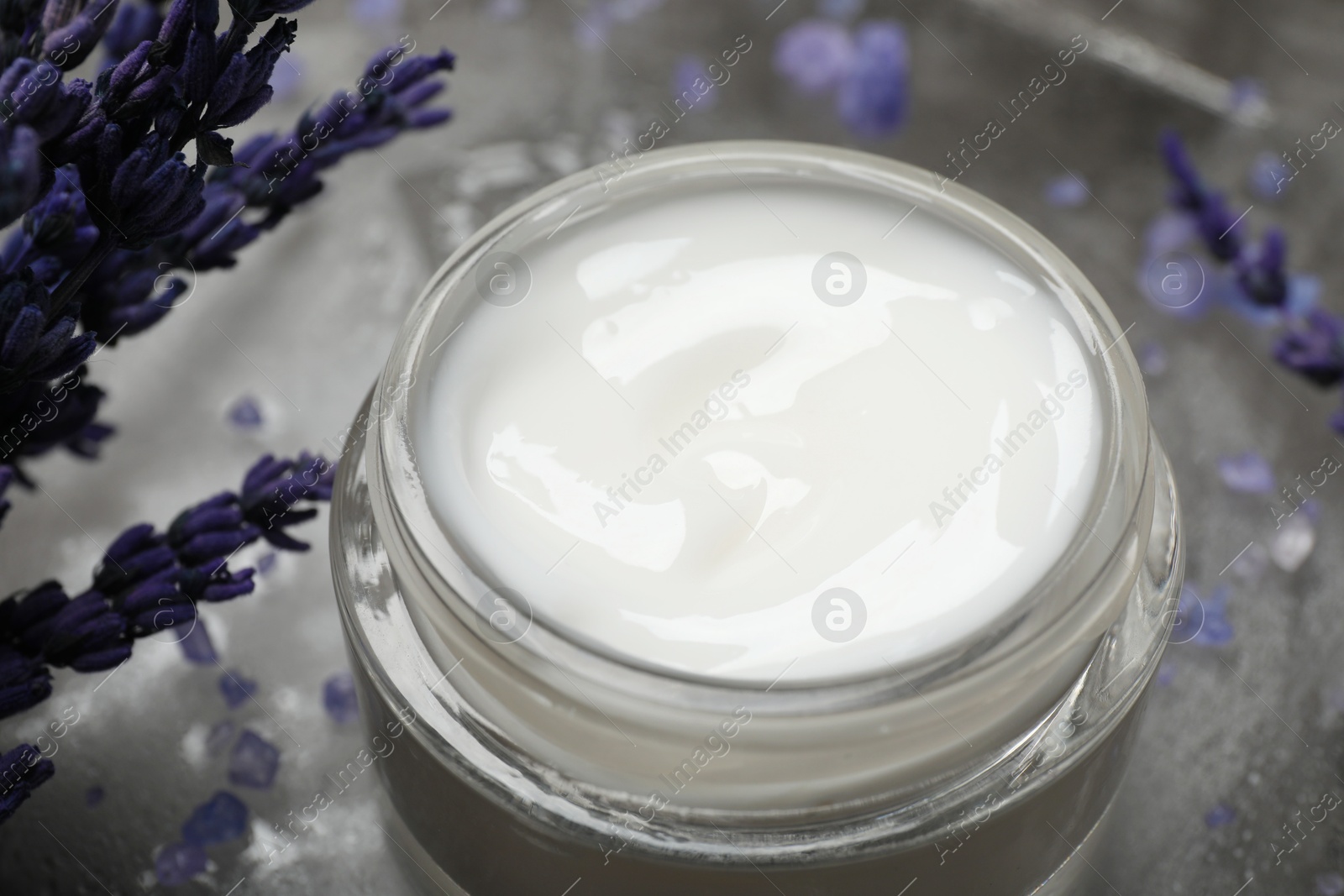 Photo of Spa composition with jar of cosmetic product and lavender flowers on grey table, closeup