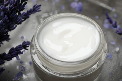 Photo of Spa composition with jar of cosmetic product and lavender flowers on grey table, closeup