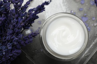 Photo of Spa composition with jar of cosmetic product and lavender flowers on grey table, flat lay