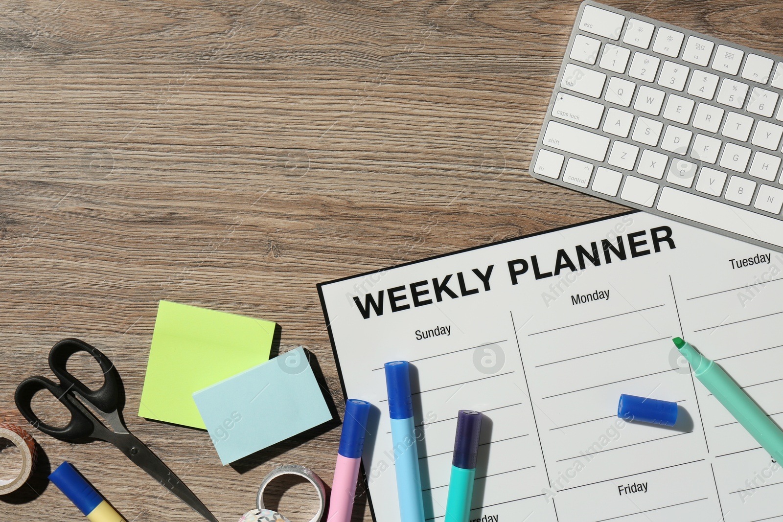 Photo of Timetable. Weekly planner, stationery and computer keyboard on wooden table, flat lay