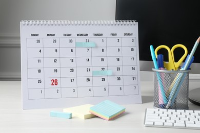 Photo of Timetable. Monthly planner, stationery and computer on white table