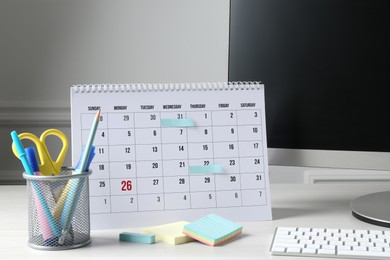 Photo of Timetable. Monthly planner, stationery and computer on white table