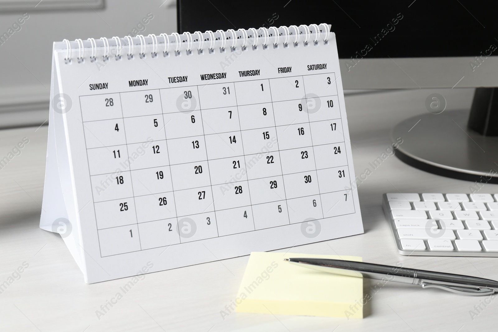 Photo of Timetable. Monthly planner, stationery and computer on white table