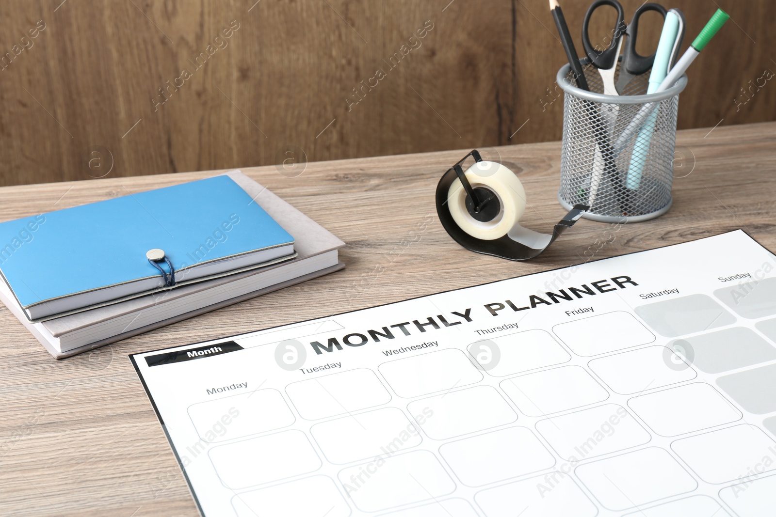 Photo of Timetable. Monthly planner and stationery on wooden table, closeup