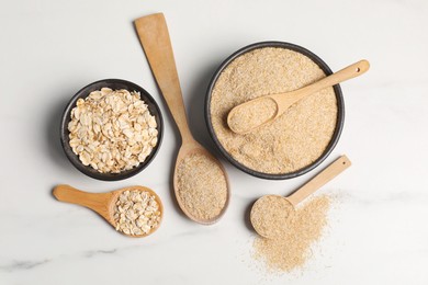 Photo of Oat bran and flakes on white marble table, flat lay