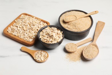 Photo of Oat bran and flakes on white marble table