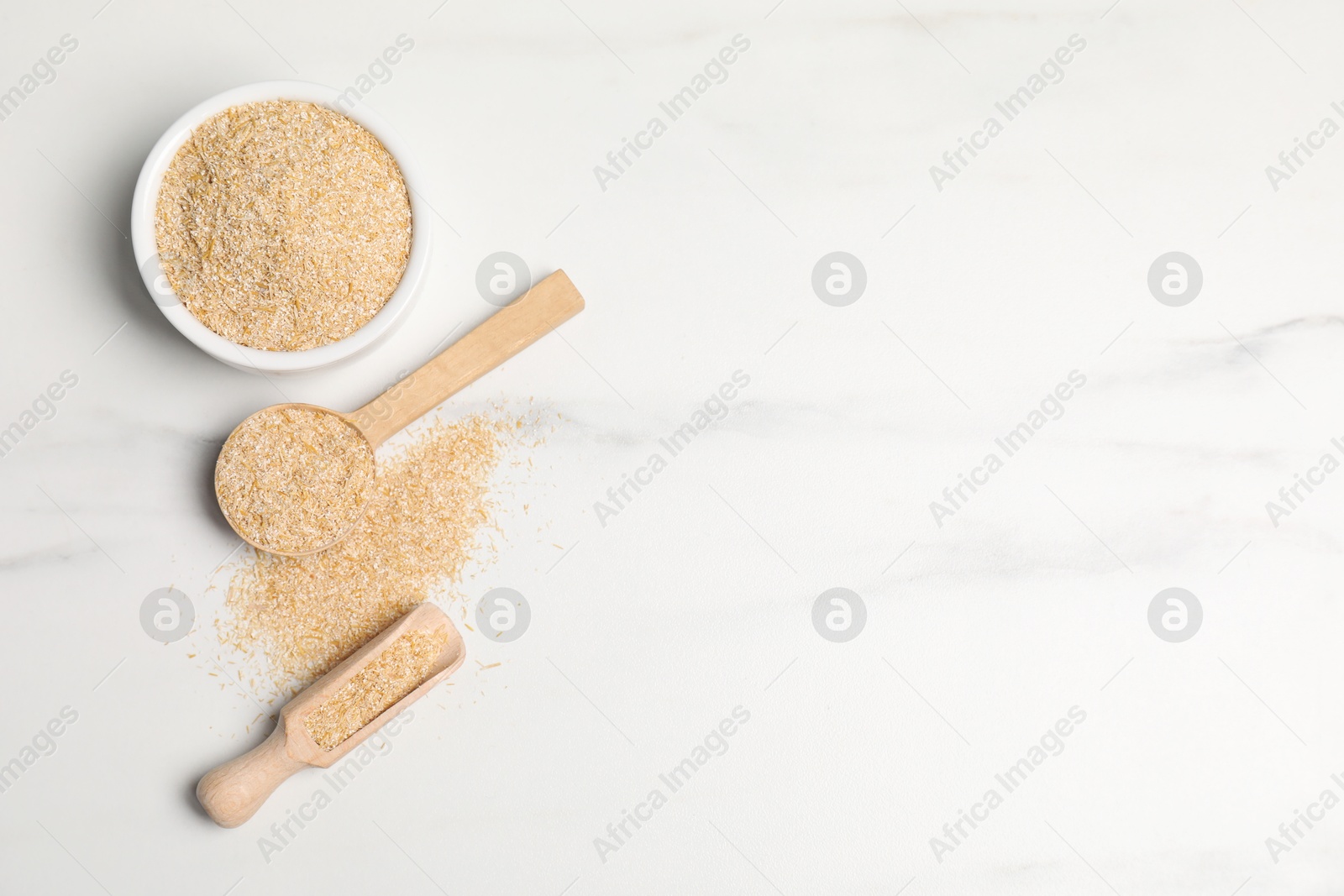 Photo of Oat bran in bowl, spoon and scoop on white marble table, top view. Space for text