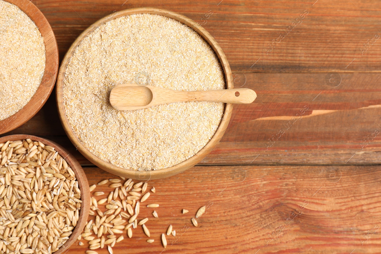 Photo of Oat bran and grains on wooden table, top view. Space for text