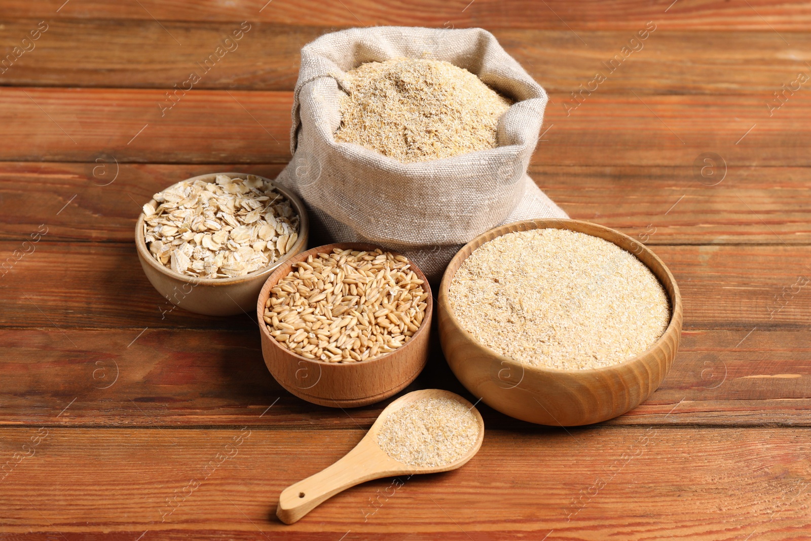 Photo of Oat bran, flakes and grains on wooden table