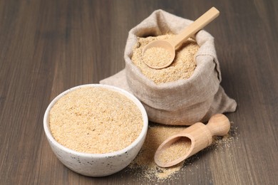 Oat bran in bowl, scoop, spoon and burlap bag on wooden table