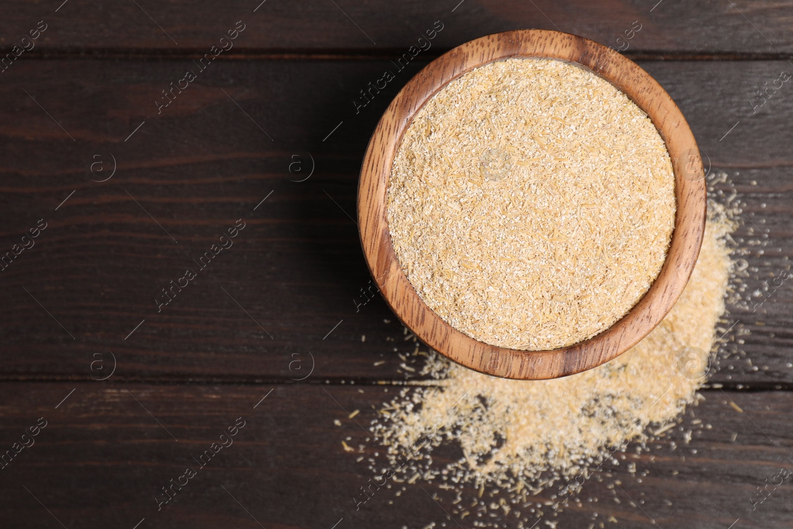 Photo of Oat bran in bowl on wooden table, top view. Space for text