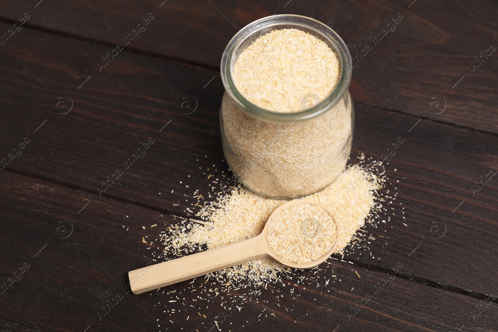 Photo of Oat bran in glass jar and spoon on wooden table