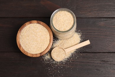 Photo of Oat bran in glass jar, bowl and spoon on wooden table, above view