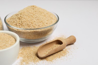 Photo of Oat bran in bowls and wooden scoop on white background