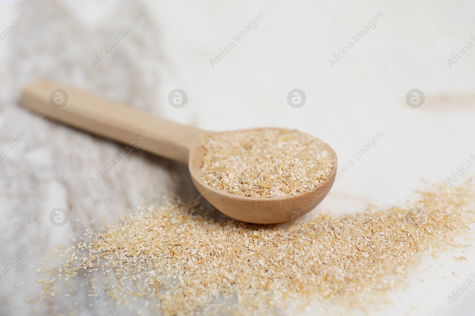 Photo of Oat bran in wooden spoon on table, closeup