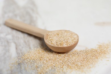 Photo of Oat bran in wooden spoon on table, closeup