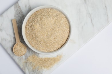 Photo of Oat bran in bowl and spoon on white table, top view