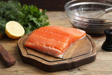 Photo of Salmon fillet and other products on wooden table, closeup