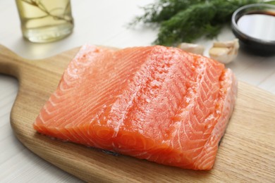 Photo of Salmon fillet and other products on wooden table, closeup