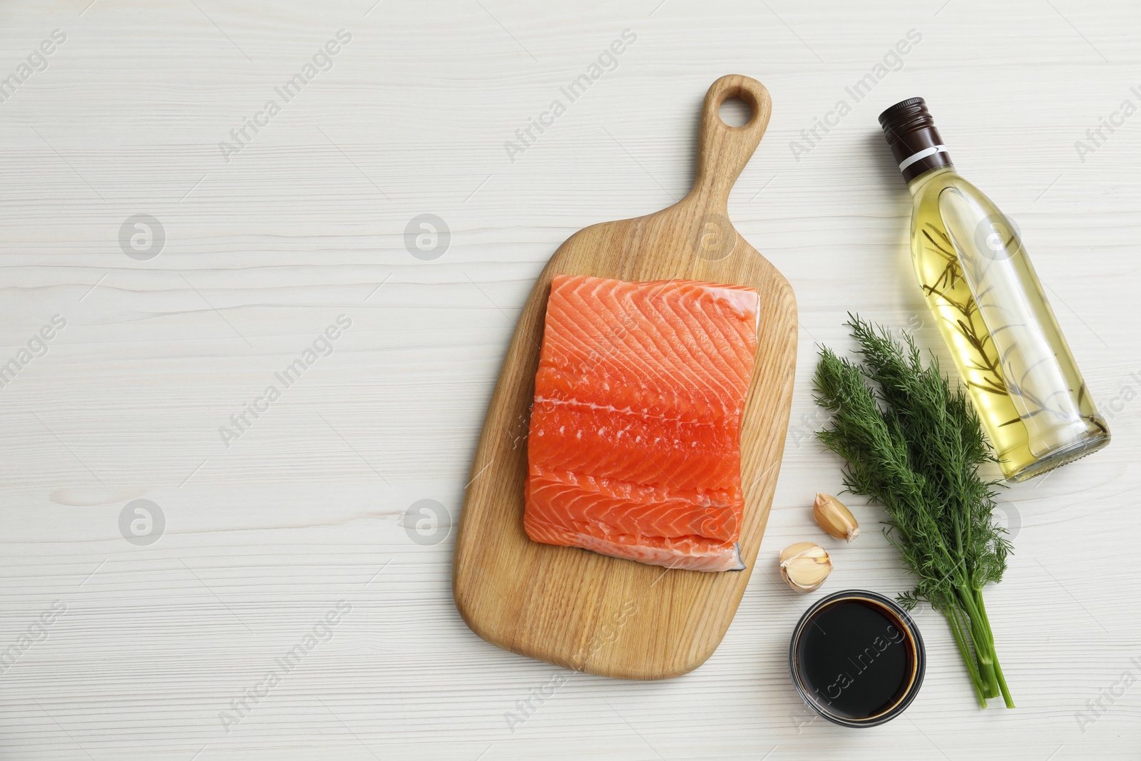 Photo of Salmon fillet, oil, soy sauce and spices on light wooden table, flat lay. Space for text