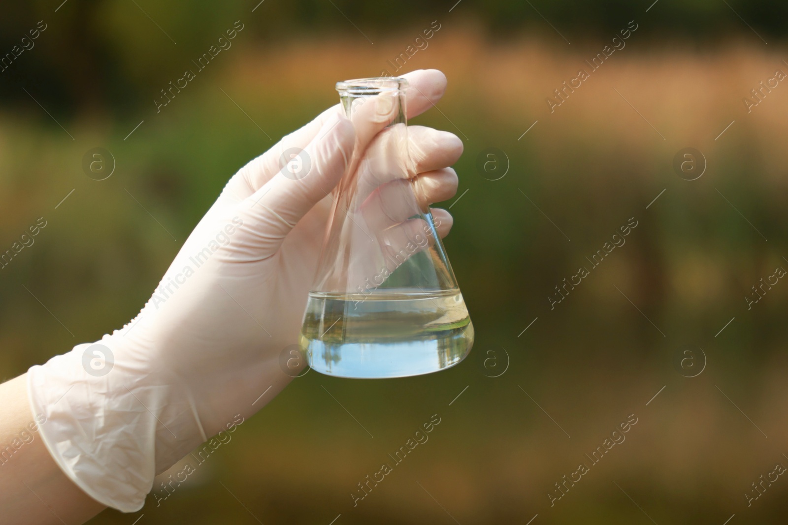 Photo of Examination of water quality. Researcher holding flask with sample outdoors, closeup