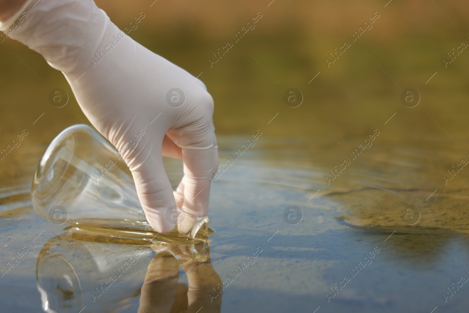 Photo of Examination of water quality. Researcher taking water sample from lake outdoors, closeup. Space for text