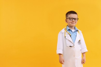 Little boy with stethoscope pretending to be doctor on yellow background, space for text. Dreaming of future profession