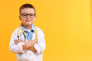 Photo of Little boy with stethoscope pretending to be doctor on yellow background, space for text. Dreaming of future profession