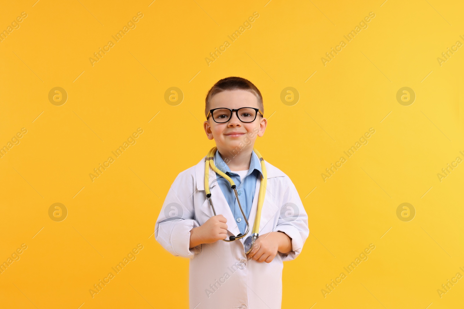 Photo of Little boy with stethoscope pretending to be doctor on yellow background. Dreaming of future profession