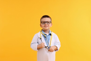 Photo of Little boy with stethoscope pretending to be doctor on yellow background. Dreaming of future profession