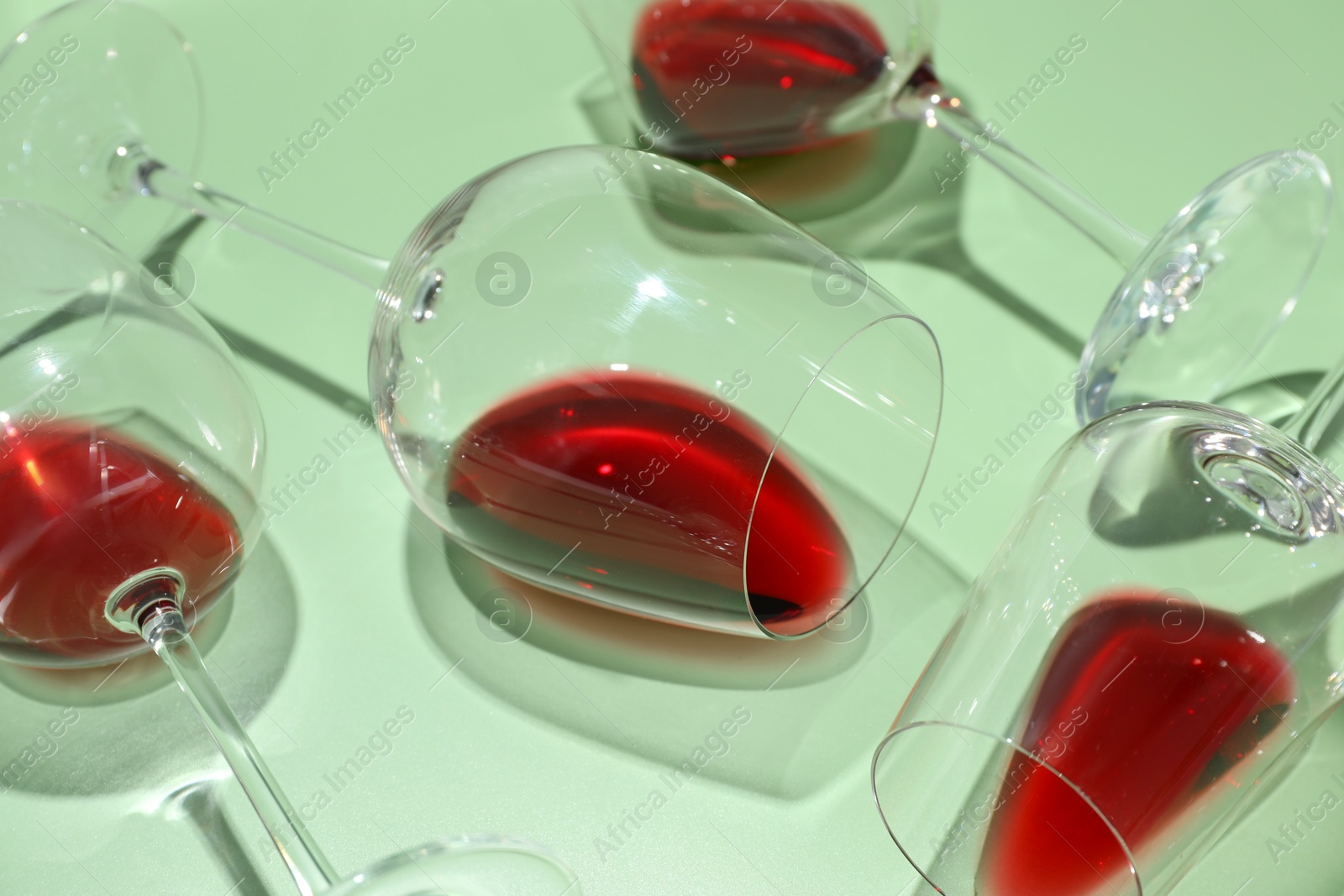 Photo of Glasses of red wine on light green background, closeup