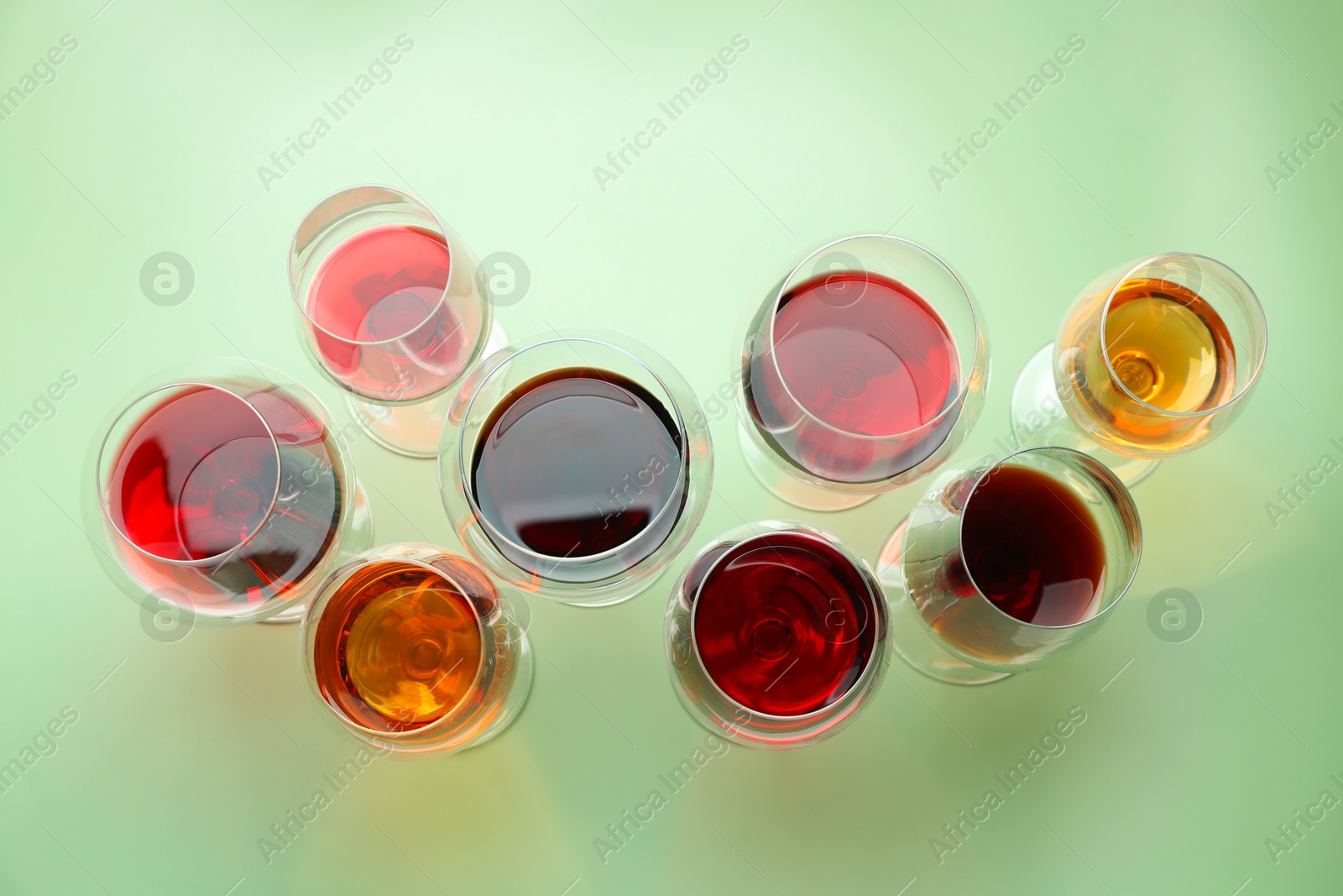 Photo of Glasses of different drinks on light green background, flat lay