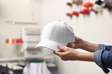 Photo of Woman with blank baseball cap for print indoors, closeup