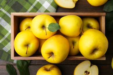 Photo of Ripe yellow apples in crate on wooden table, top view