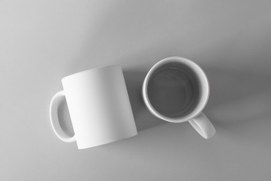 Photo of Two blank white mugs on light background, top view. Mockup for design