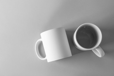 Photo of Two blank white mugs on light background, top view. Mockup for design