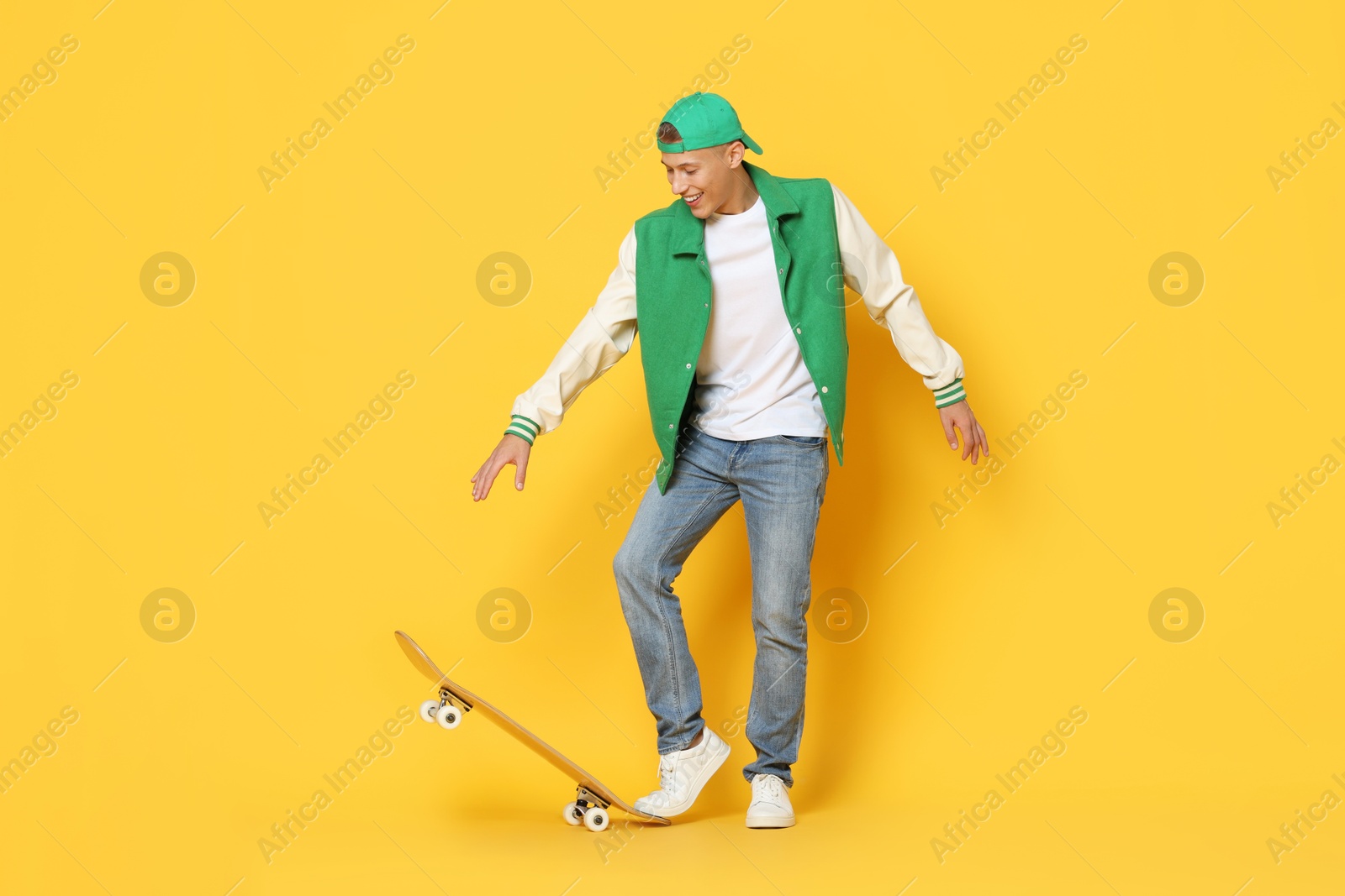 Photo of Happy man with skateboard on orange background