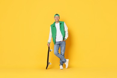 Happy man with skateboard on orange background