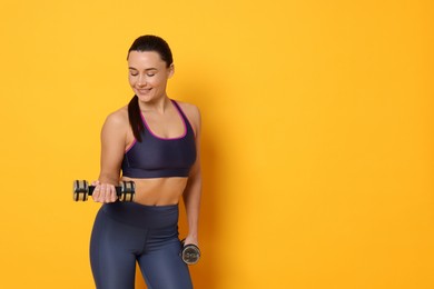 Photo of Smiling woman with dumbbells training on yellow background. Space for text