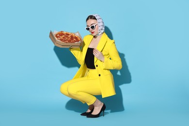 Photo of Stylish woman with delicious pizza on light blue background