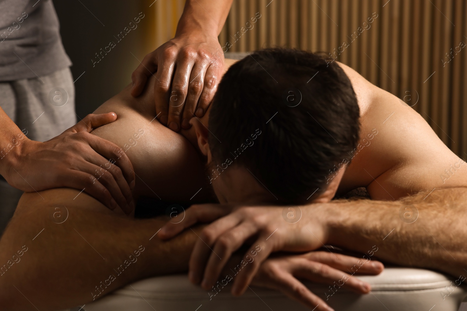 Photo of Professional physiotherapist doing shoulder massage for his client indoors, closeup